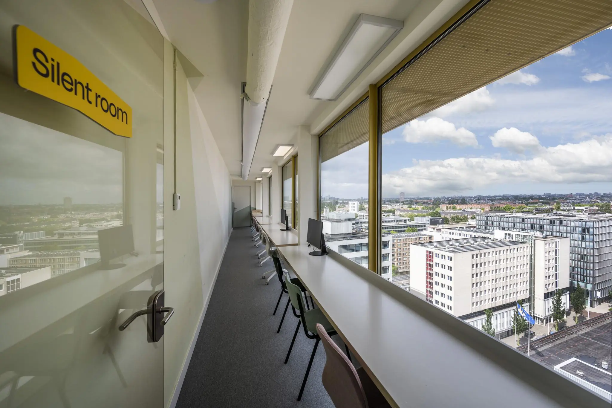 Stille werkruimte met bureaus en computers aan een raam met uitzicht op de stad, gelegen aan de James Wattstraat.